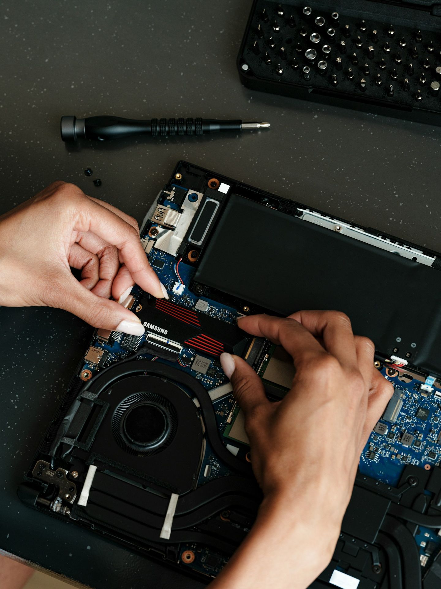 A person working on a laptop with a screwdriver